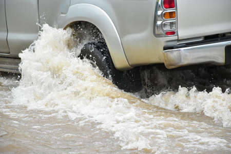 Vehicles are passing the road which fulled of floodwater. Concept for car insurance, safty and...