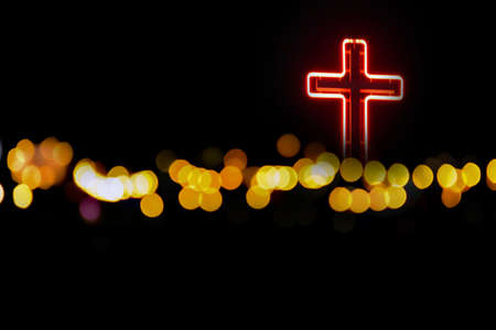The cross is adorned with lamps at night, beside the road with bokeh traffic lights in northern province, Thailand.の写真素材