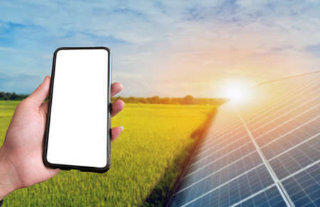 Mockup Mobile phone holding in hand with blurred solar roof background, concept for using smart devices with solar system at home, at work, on application and in daily life.の写真素材