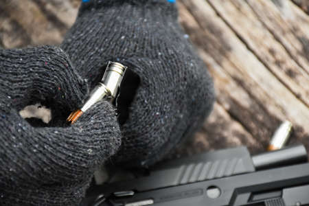 Two hands reloading 9mm bullets full metal jacket rounds into a black magazine. Soft and selective...