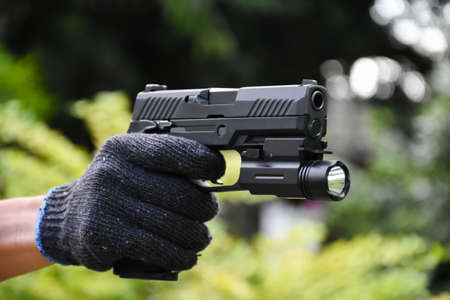 9mm automatic pistol holding in hand, copy space, soft and selective focus on pistol.