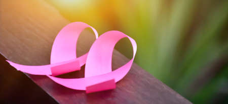 Pink ribbons on wooden table, sunlight and blurred background, concept for breast cancer awareness around the world. Soft and selective focus on pink ribbons.の写真素材