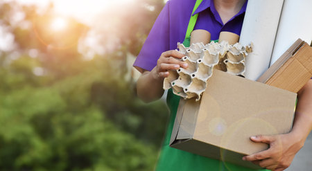 Houseowner is separiting bottles, paper, egg cartons and other stuffs in the black plastic bag in front of the house, concept for reducing global warming, saving our world, soft and selective focus.の写真素材
