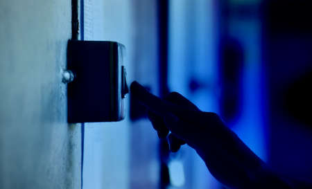 Homeowner is pulling down the circuit breaker on the wall from on to off, concept for saving energy at home. Soft and selective focus.の写真素材