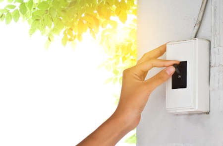 Homeowner is pulling down the circuit breaker on the wall from on to off, concept for saving energy...