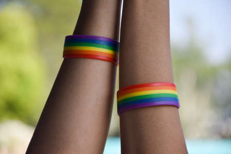 Rainbow wristbands in wrists of asian boy couple with blurred background, concept for celebration of lgbtq+ community in pride month or in June around the world.の写真素材