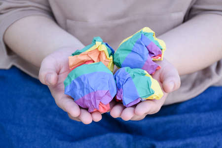 Paper balls made of wringled rainbow colored paper are holding in hands of the LGBT person, concept for lgbtq+ communities celebrations in pride month around the world.の写真素材