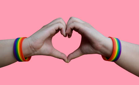 lgbt, same-sex love and homosexual relationships concept - close up of male hands with gay pride rainbow awareness wristbands showing heart gesture with clipping pathsの写真素材
