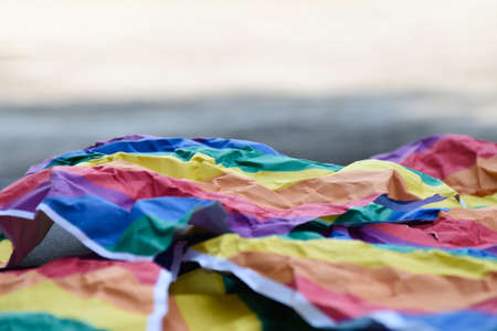 Closeup view of a wrinkled sheet of rainbow paper which was left by the side of the road. concept for lgbt celebrations in pride month, soft and selective focus.の写真素材