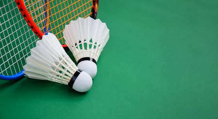 Badminton rackets and white cream shuttlecock feather on green floor, selective focus on badminton rackets and string.の写真素材