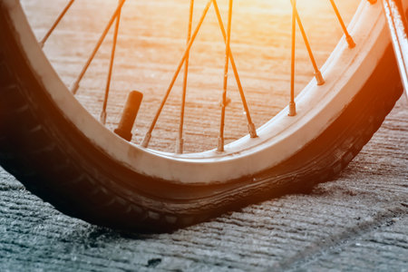 Bike flat tire parked on pavement by the rural road, sunlight edited, soft and selective focus on bike spokes.の写真素材