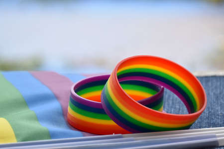 Rainbow wristbands, symbol of lgbtq+, on rainbow flags and jeans, concept for lgbtq+ symbol wearing to attend the celebration events of lgbtq+ community around the world, soft and selective focus.の写真素材