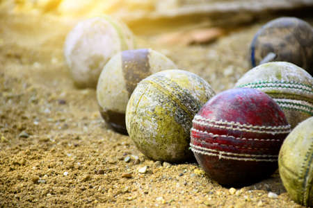 Old leather cricket balls for training and practising on sand floor beside the court, soft and selective focus on red cricket ball.の写真素材