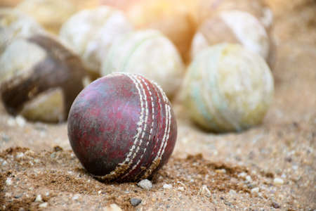 Old leather cricket balls for training and practising on sand floor beside the court, soft and selective focus on red cricket ball.の写真素材