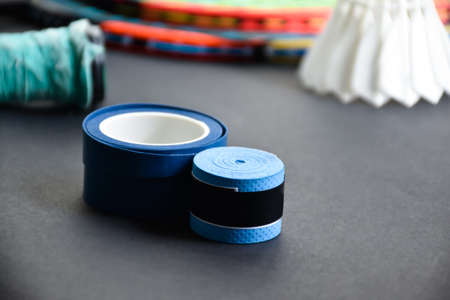 Blue plastic handgrip to wrap around the badminton racket on dark floor of badminton indoor court, soft and selective focus on grip, concept for badminton sport lovers around the wの写真素材
