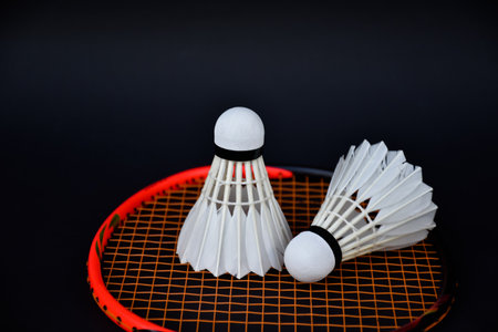 White cream badminton shuttlecock and badminton rackets on dark floor of indoor badminton court, soft and selective focus, concept for badminton sport lovers around the worldの写真素材