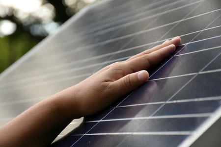 Closeup hand on photovoltaic or solar cell panel, soft and selective focus on hand, self photovoltaic panel checking by touch the surface, sustainable energy in human life concept.の写真素材