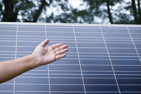 Photovoltaic or solar cell panel behind the left hand showing, soft and selective focus on hand, concept for presenting and showing the photovoltaic panel to store and use the natuの写真素材