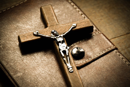 A wooden cross with a light brown leather strap rests on a wooden floor.の写真素材