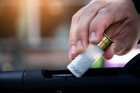 Shotgun man is inserting new shotshell bullets on shotgun, soft and selective focus.の写真素材