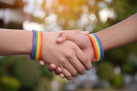 Rainbow wristband wearing in hand of young asian gay to show and represent gender diversity, to respect human rights in alternative sex, to stop punishing homosexuals in some religの写真素材