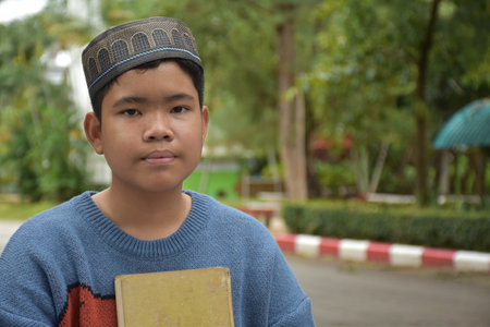 Portrait asian muslim or islamic boy sitting in the school park and smiling happily, soft and...