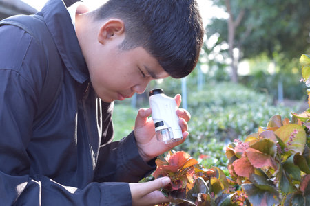Young asian man using a spray bottle to take care of plants