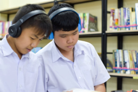 Group of school kids listening to music with headphones in the library.の写真素材