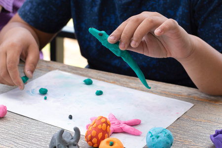 Close-up of child's hand playing with plasticine on tableの写真素材