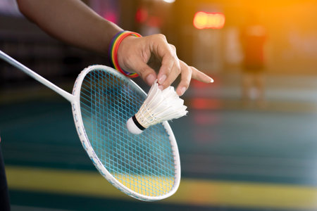 Badminton player wears rainbow wristbands and holding racket and white shuttlecock in front of the net before serving it to player in another side of the court, LGBT concept.の写真素材