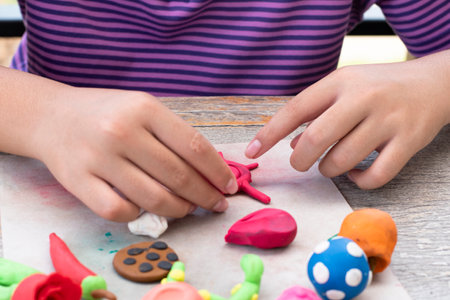 Close up view of child's hands playing with plasticine at tableの写真素材
