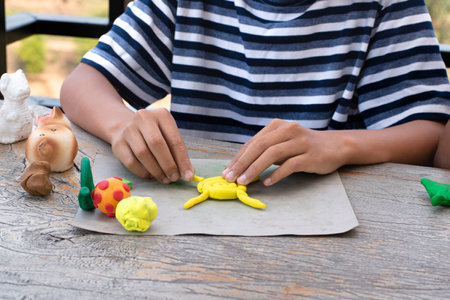 Close up of child hands playing with plasticine clay on table outdoors