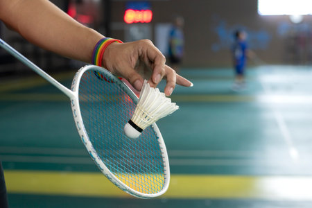 Badminton player wears rainbow wristbands and holding racket and white shuttlecock in front of the net before serving it to player in another side of the court, LGBT concept.の写真素材