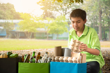 Young asian boy collecting plastic waste in the park. Recycling concept