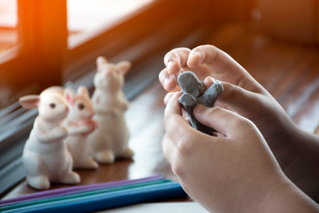 An autistic boy molding different shapes of colored plasticine at home to develop slower brain than...