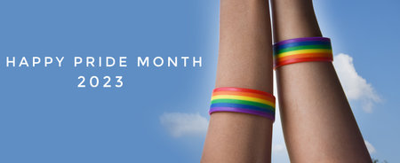 Happy Pride Day banner. LGBT rainbow wristband on woman's legsの写真素材