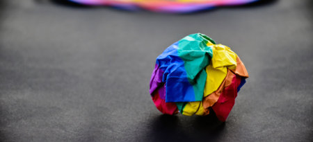 Colorful crumpled paper ball on black background, creative concept