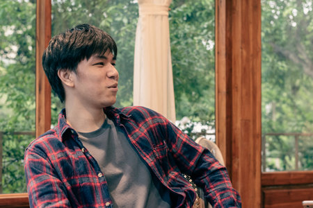 Young Asian man in checkered shirt sitting at the cafe.の写真素材