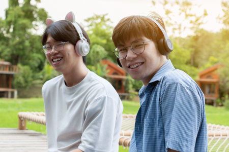 Happy asian young men listen to music with headphones in the park.の写真素材