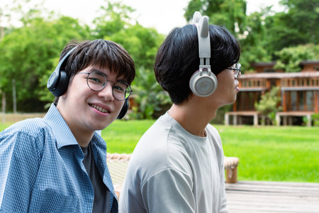 Young asian man listening to music with his friend in the parkの写真素材