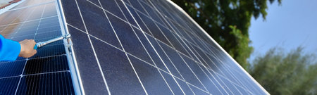 Panoramic image of a man installing solar panels on the roof