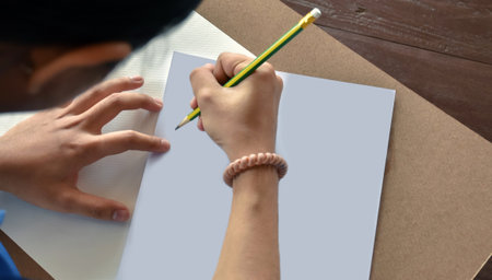 Close up of a young man drawing with pencils on white paper