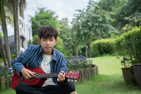 Young asian man playing guitar in the garden at home, lifestyle concept.の写真素材