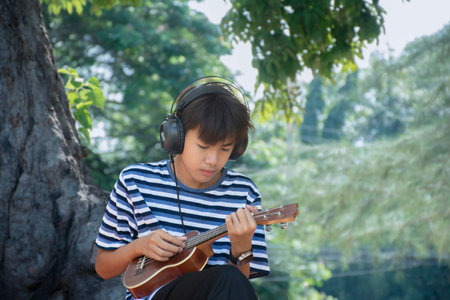Young asian boy playing ukulele in the park.の写真素材