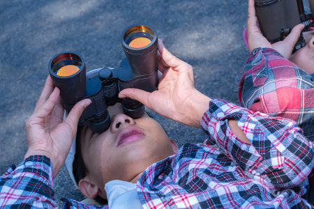 A boy looking through binoculars in the park. Selective focus.の写真素材