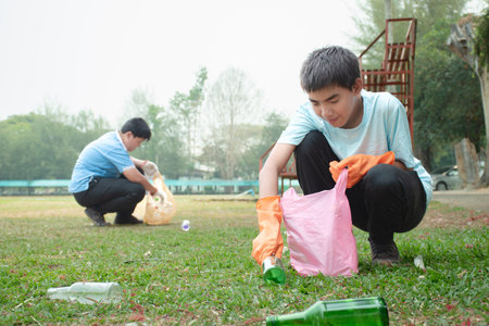 Cute asian boy and his friend cleaning the park with plastic garbage