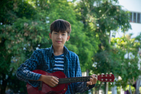 Young asian boy playing guitar in the park. Music concept.の写真素材