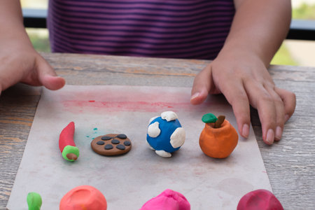 Close up of child's hands playing with plasticine at table outdoorsの写真素材