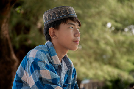 portrait of asian boy in blue shirt and cap looking awayの写真素材