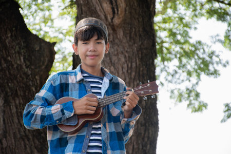 Young asian boy playing ukulele in the park.の写真素材